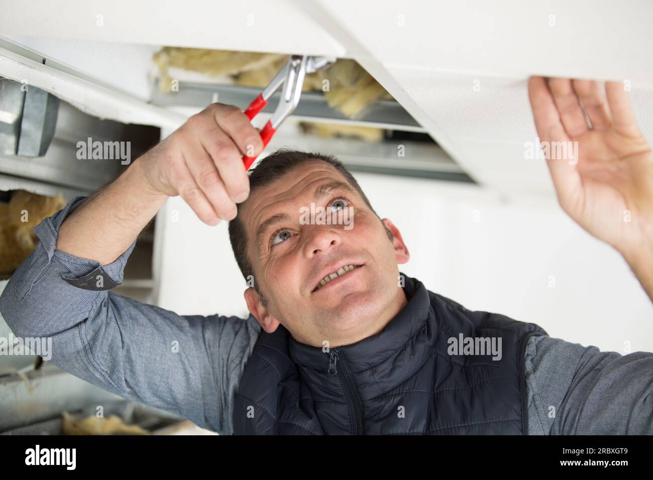 male builder using pliers through roof panel Stock Photo