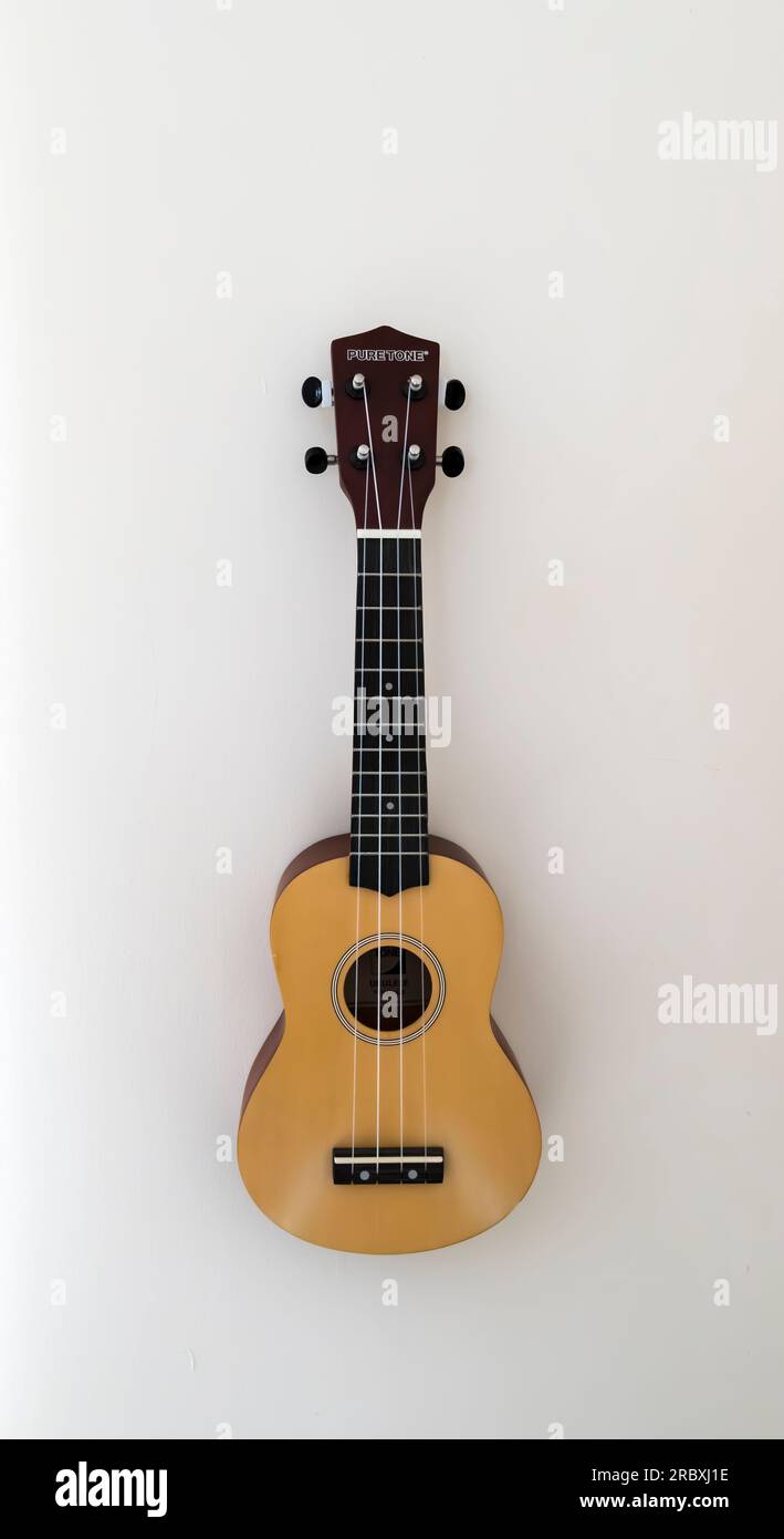 Pure Tone Ukulele hanging on wall. Stock Photo