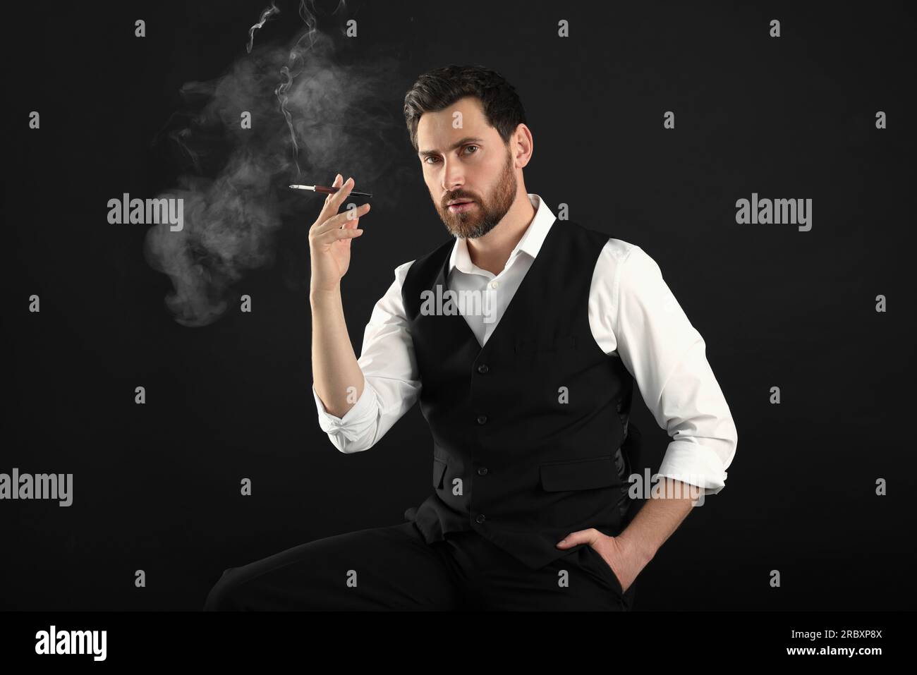 Man using cigarette holder for smoking on black background Stock Photo