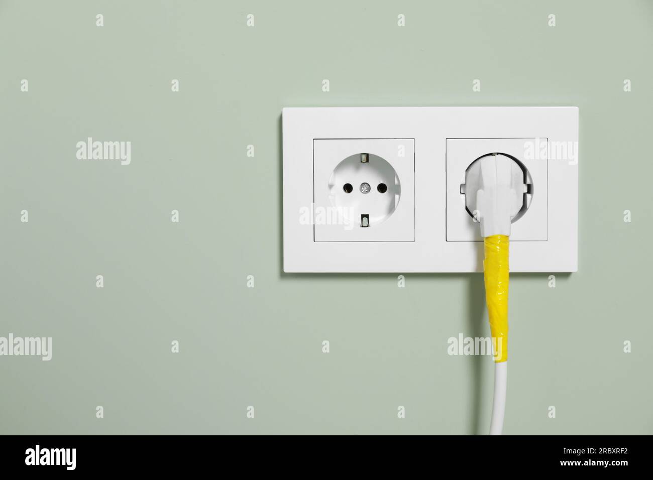 Power plug with yellow adhesive tape wrapped around wire in socket on