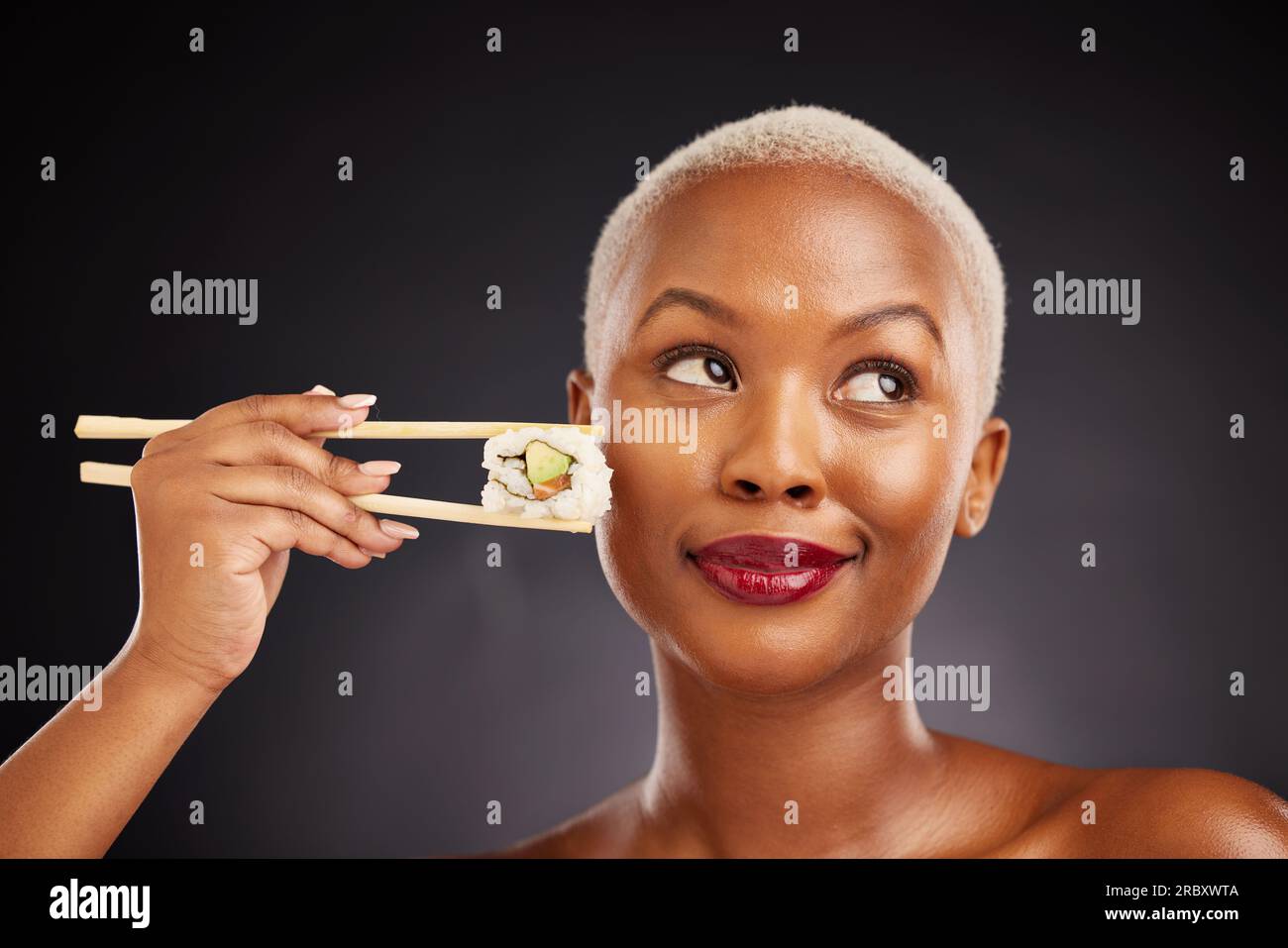 Woman, thinking and sushi with chopsticks in studio for healthy eating ...