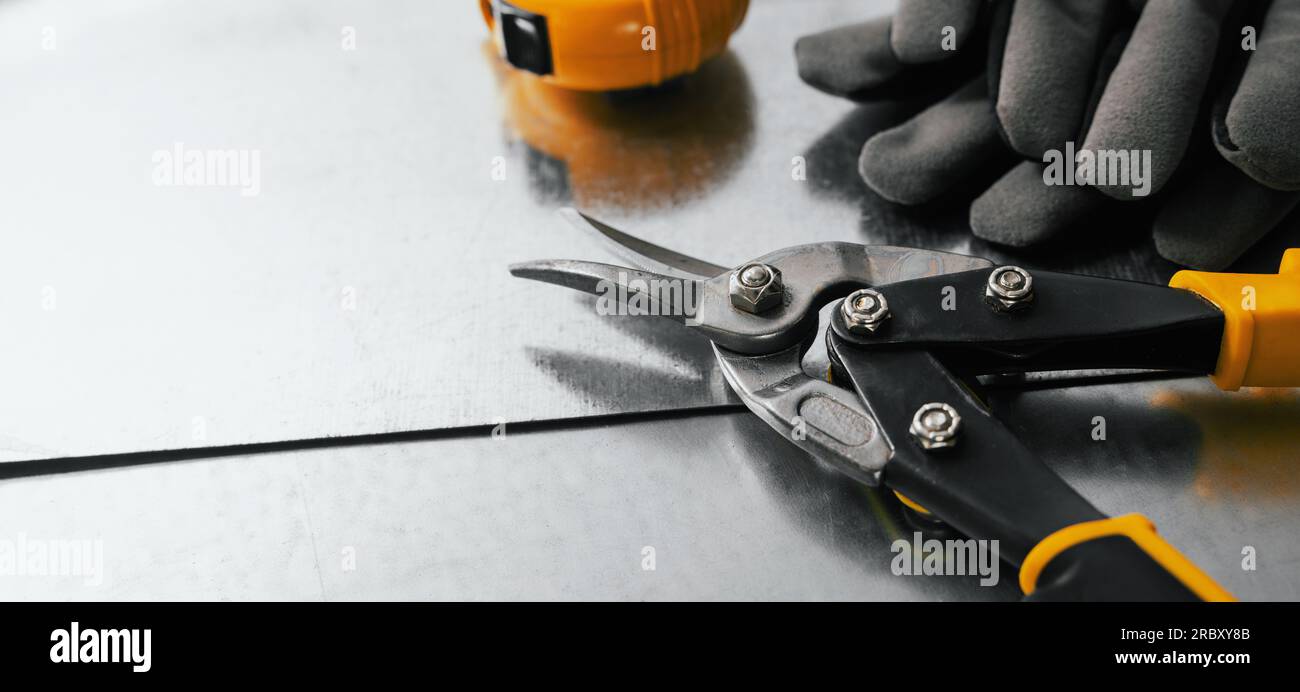 tinsmith and metal works. tin snips, gloves and ruler on metal sheets. banner with copy space Stock Photo