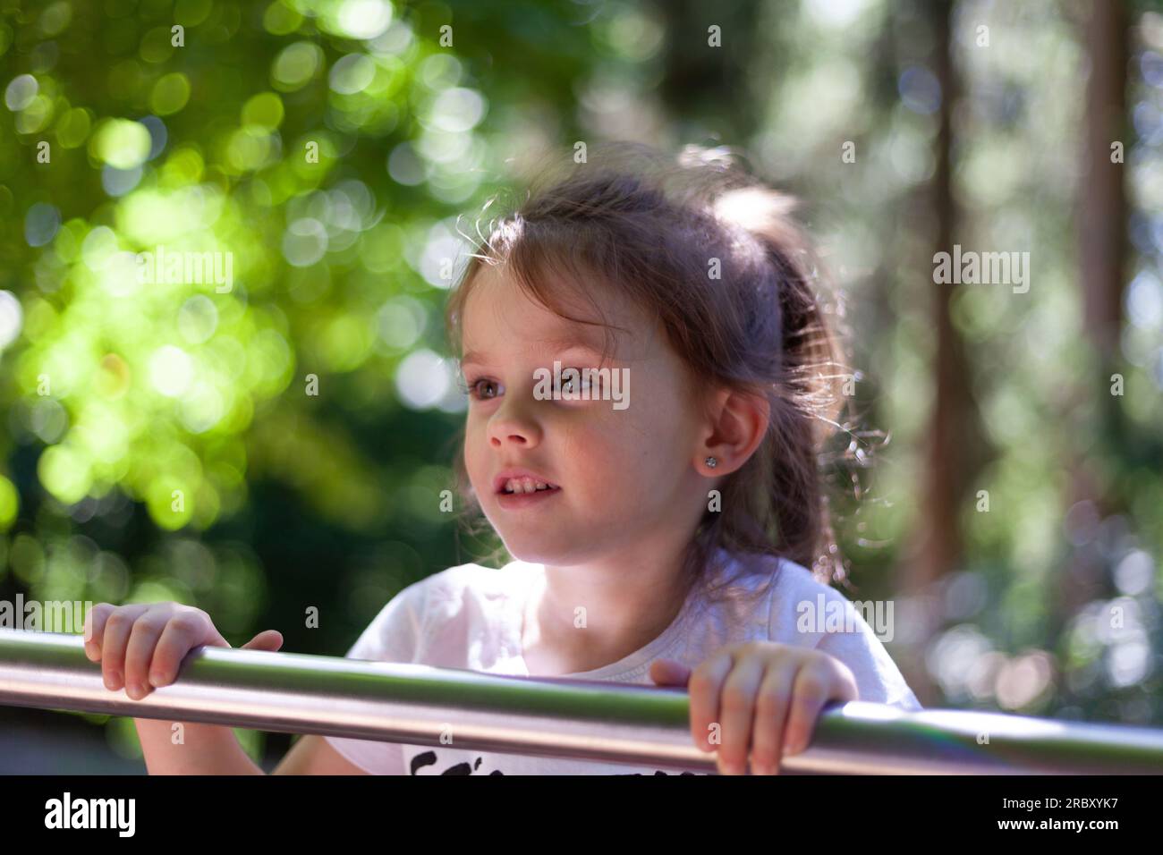 Portrait of a cute little girl playing on the playground in summer ...