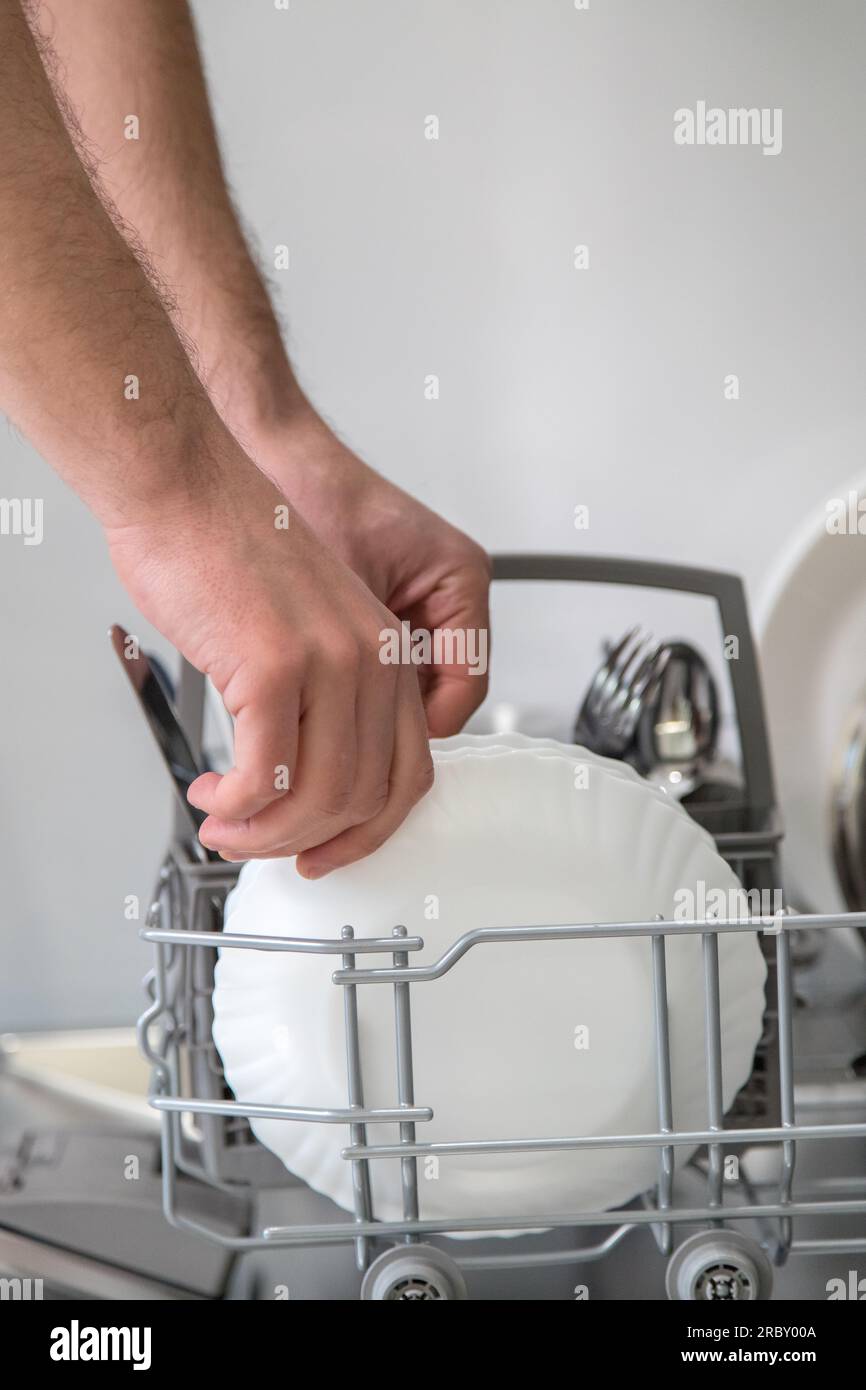 Dishwasher open and a person removing the washed dishes. Concept of