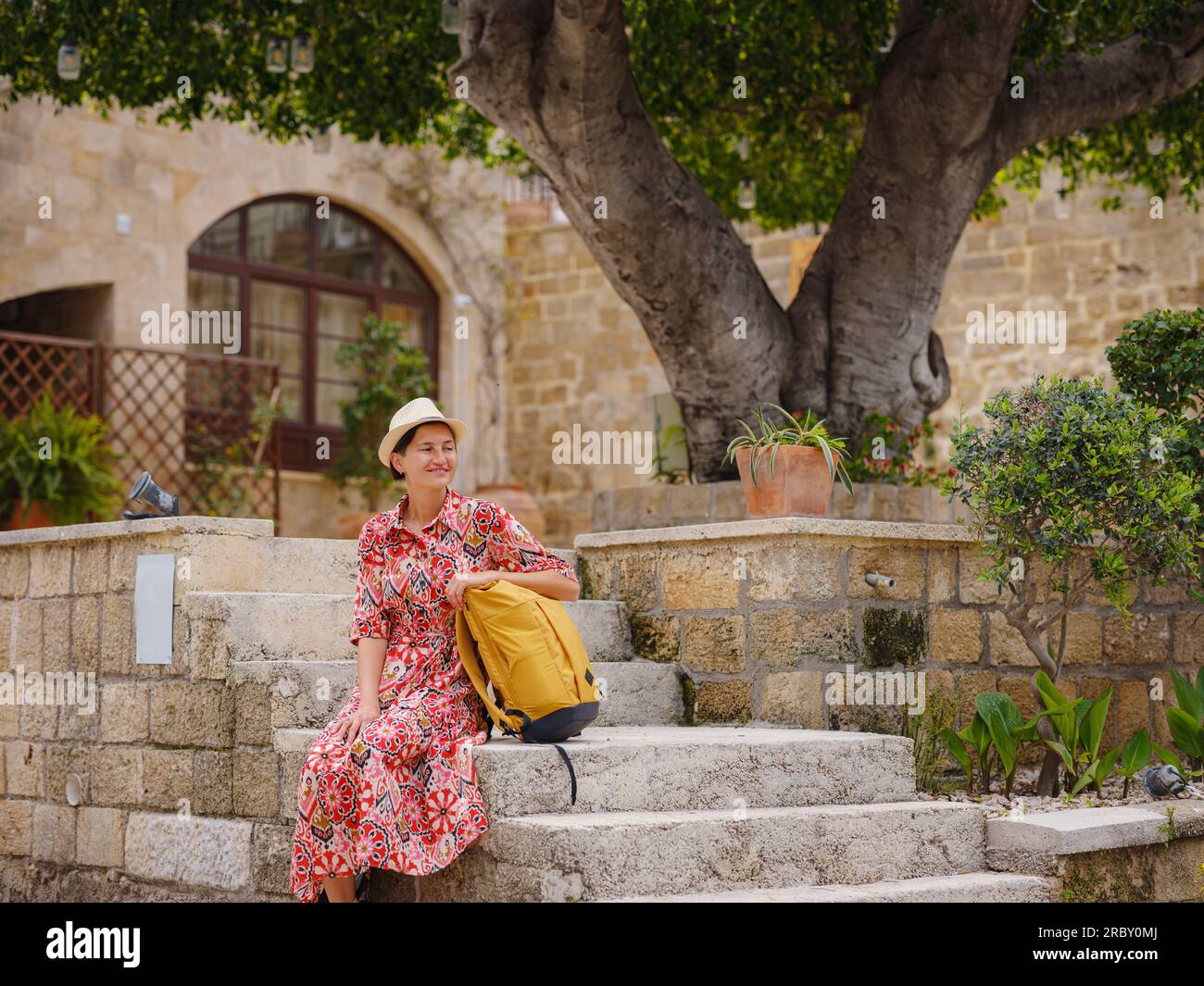 Rhoades Steps Young Asian woman in red dress walks through streets of Rhodes. woman ...