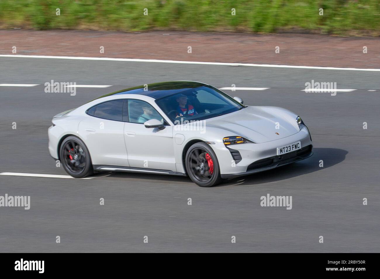 White Porsche Taycan (J1), all-electric Porsche Taycan Turbo S (model year 2023) in Carrara White Metallic; travelling at speed on the M6 motorway in Greater Manchester, UK Stock Photo