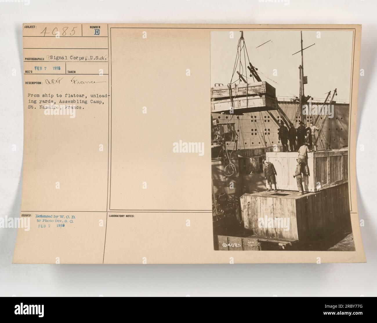 Soldiers unloading equipment and supplies from a ship onto flatcars in ...