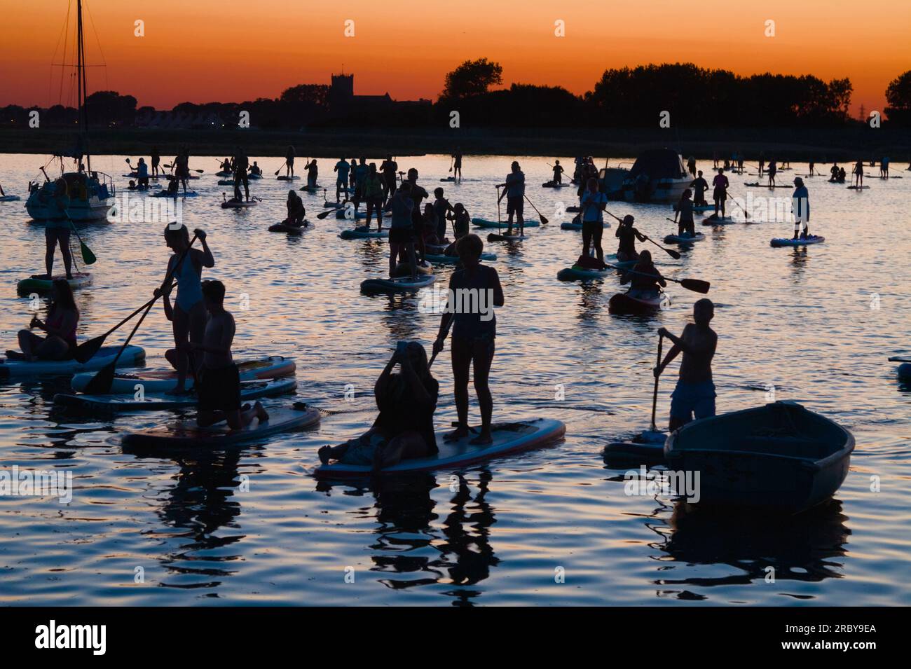Large Group Of Stand UP Paddleboarders In Stanpit Creek At Sunset Christchurch Harbour, UK Stock Photo