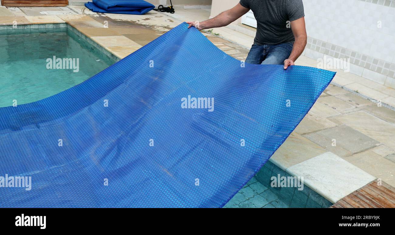 Man removing swimming pool cover and folding protector Stock Photo