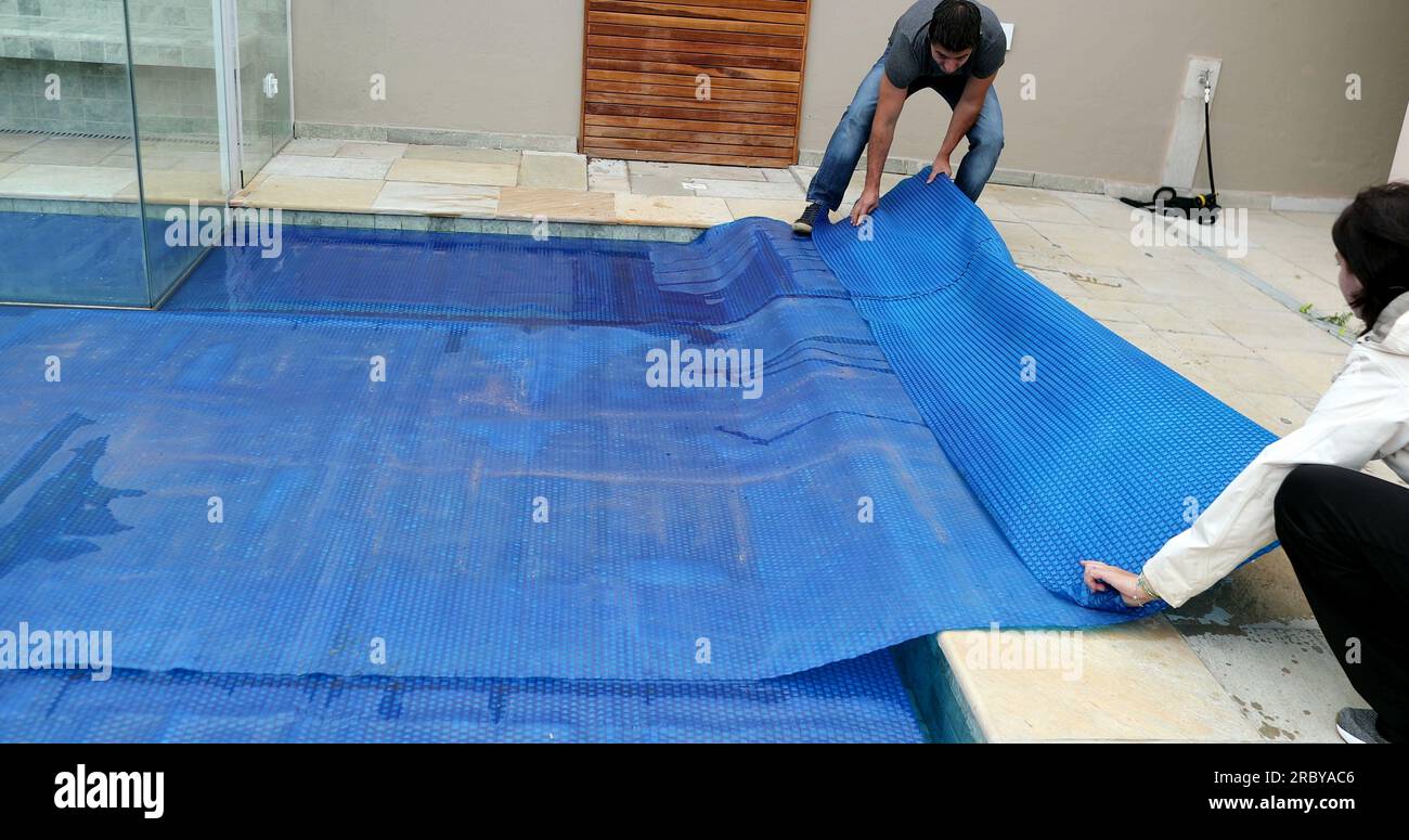 People removing swimming pool cover Stock Photo Alamy