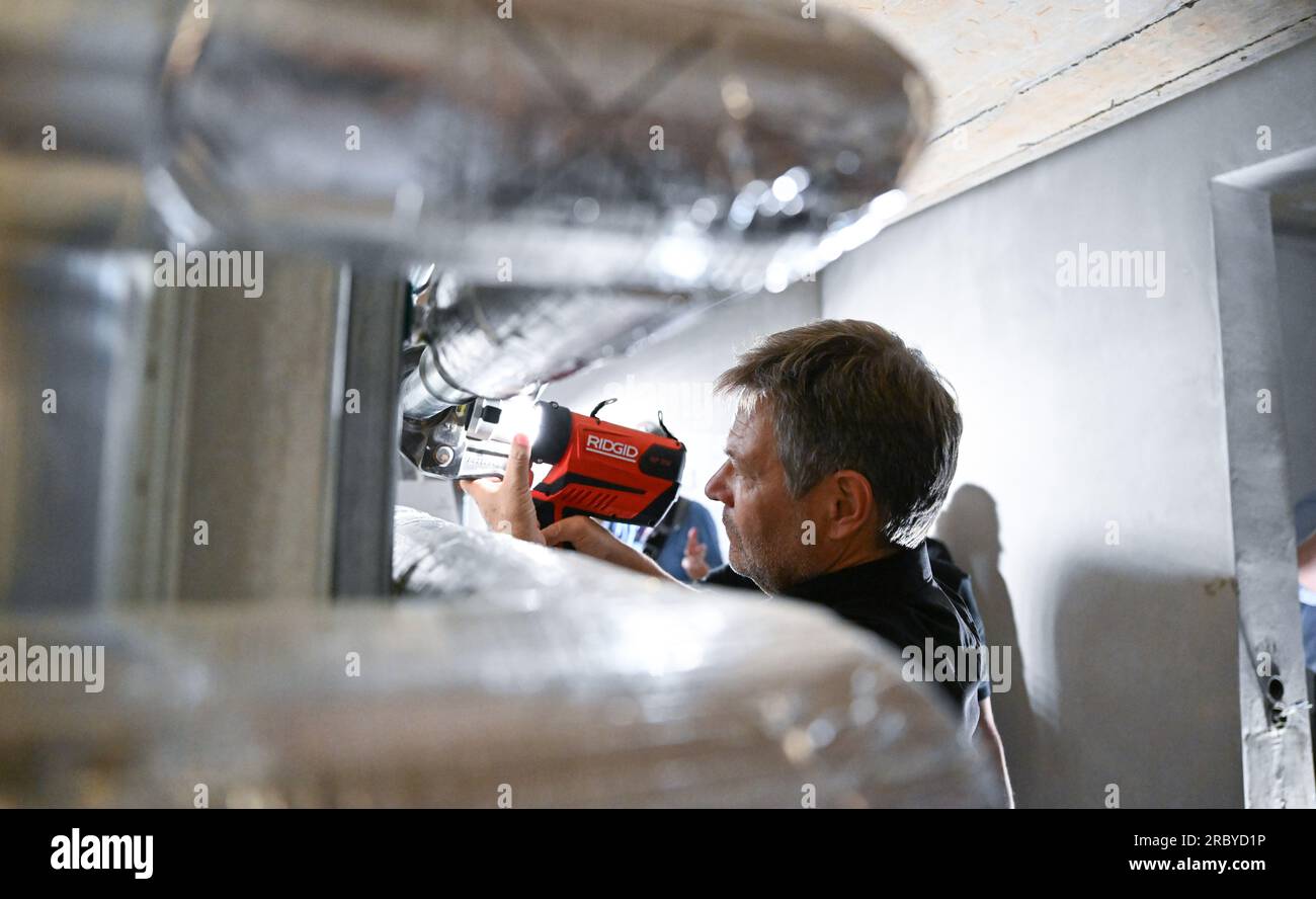 Cologne, Germany. 11th July, 2023. During his summer trip, Robert Habeck (Bündnis 90/Die Grünen), Federal Minister for Economics and Climate Protection, is shown insulating pipes in a heating cellar at the Temperaturwerk für Heiztechnik craftsman's workshop, where he lends a hand. Credit: Bernd Weißbrod/dpa/Alamy Live News Stock Photo