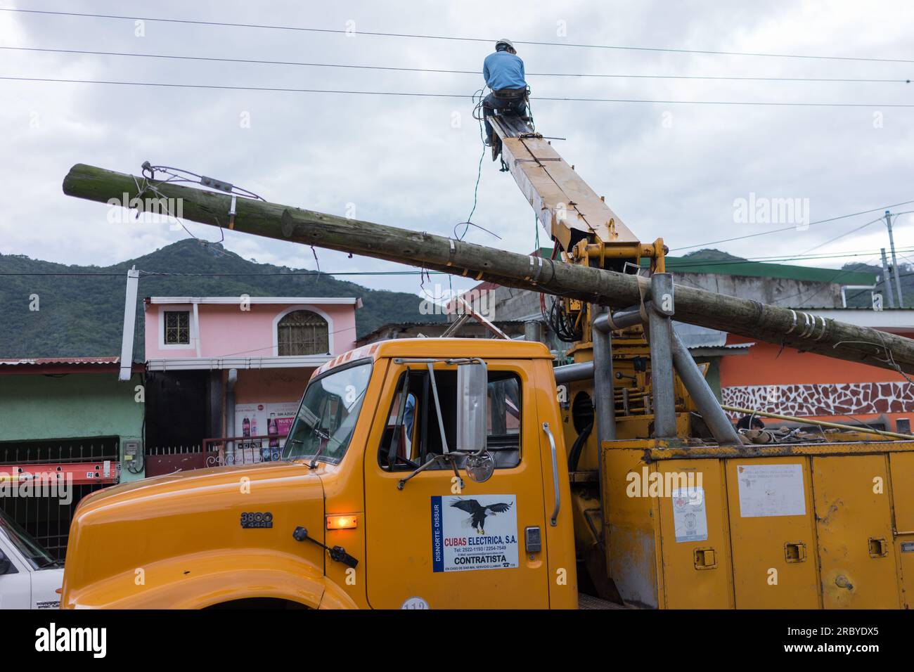 A Nicaraguan work sit on the top of a extensible support to reach wires while working on replacing a telephone pole. Stock Photo