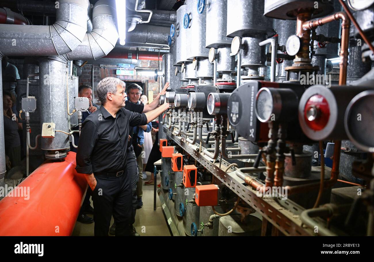 Cologne, Germany. 11th July, 2023. Robert Habeck (l, Bündnis 90/Die Grünen), Federal Minister of Economics and Climate Protection, has modern heating technology explained to him by Managing Director Marco Goetzke (r) in a heating cellar during his summer trip to the Temperaturwerk für Heiztechnik craft workshop. Credit: Bernd Weißbrod/dpa/Alamy Live News Stock Photo