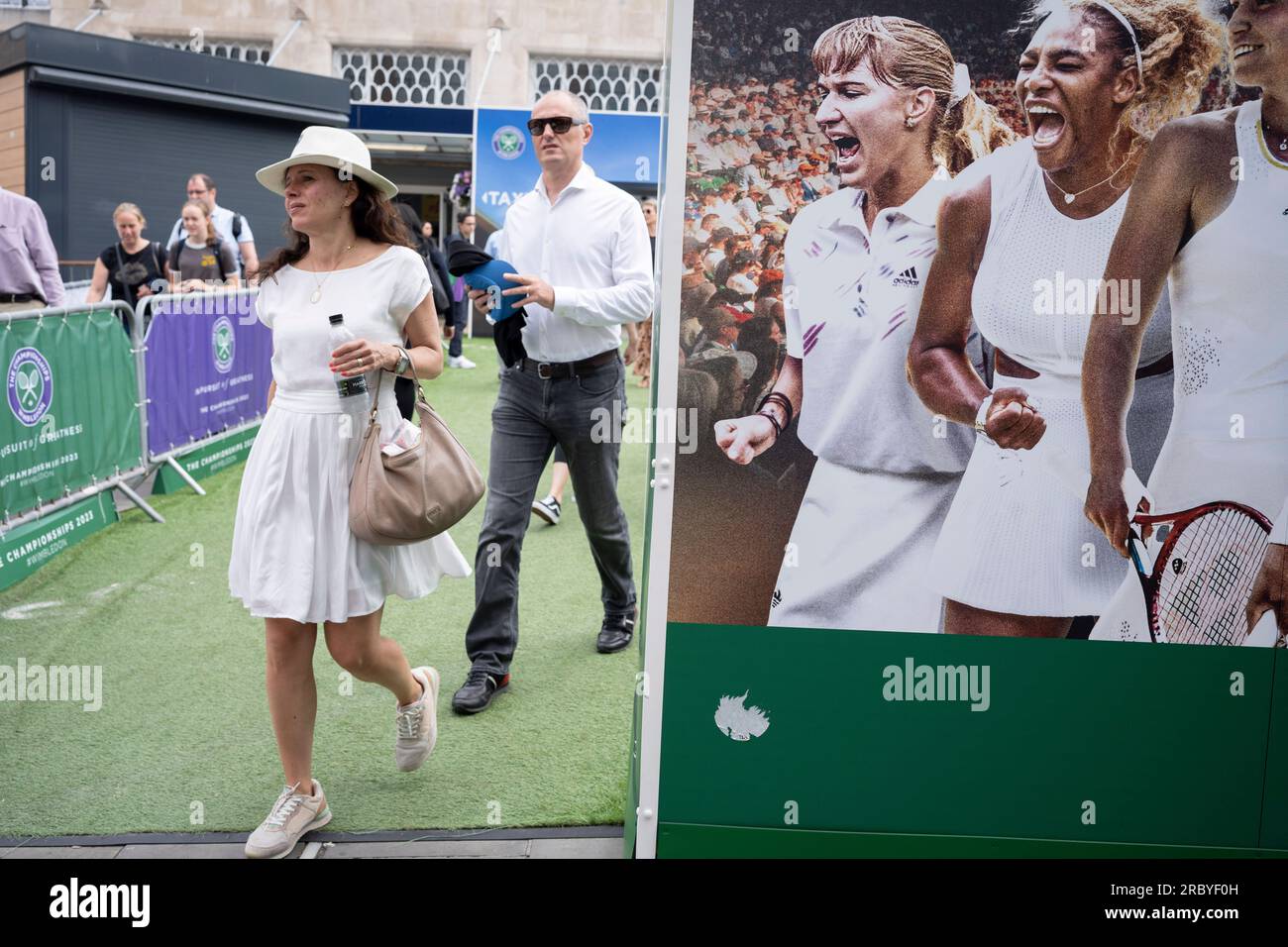 Visitors to Wimbledon station pass a billboard featuring past women