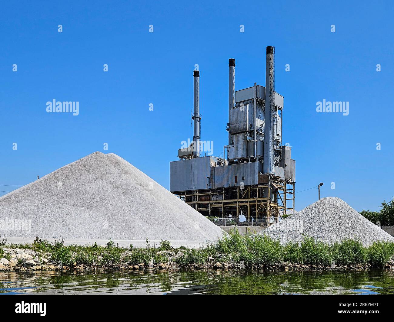 Piles of white limestone at water's edge by the dismantled power plant in Michigan Stock Photo