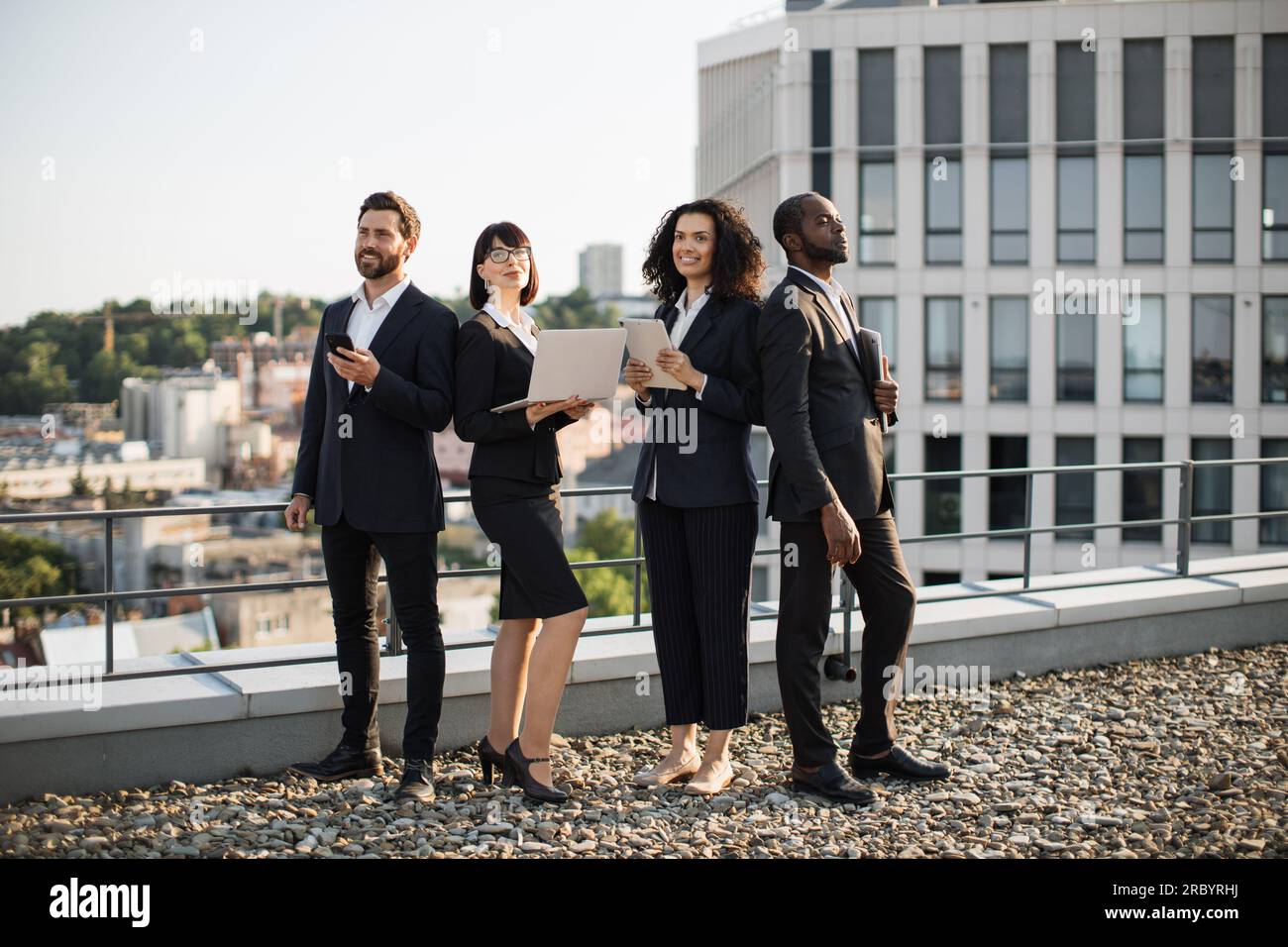 Four diverse corporate partners standing on rooftop with fantastic city ...