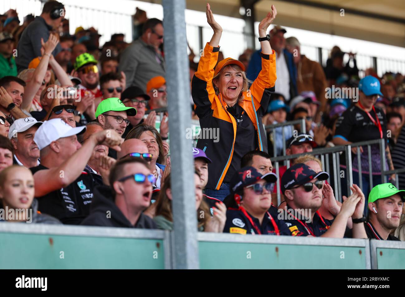 A women Grand Prix fan dressed in McClaren colours stands and claps and cheers as Lando Norris (GBR) of McLaren F1 Team passes in 2nd place  during th Stock Photo