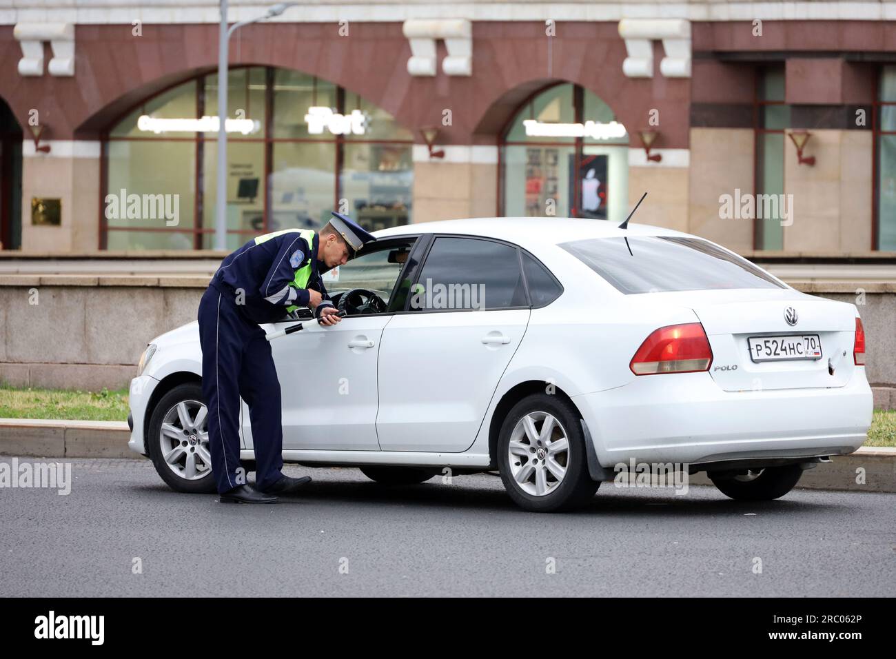 Traffic police officer checks the documents of a car driver. Policeman patrol the city street in summer Stock Photo