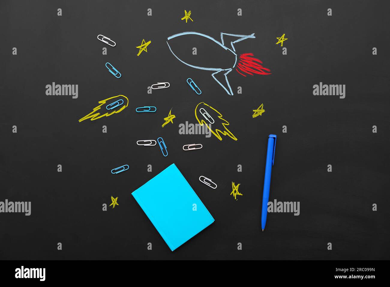 Creative composition with drawn rocket and different stationery on black chalkboard Stock Photo
