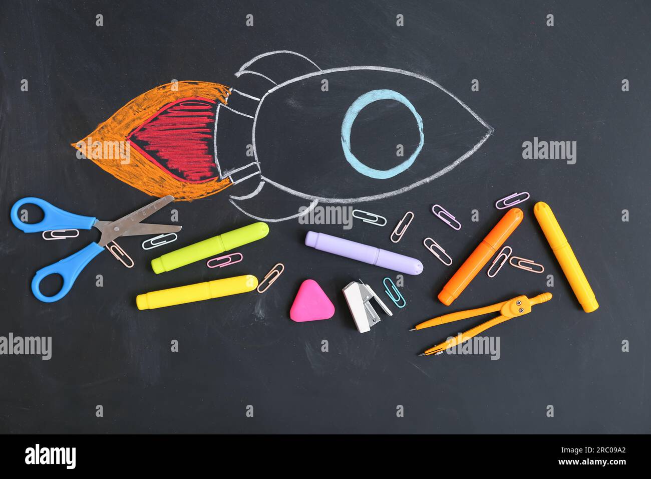 Creative composition with drawn rocket and different stationery on black chalkboard Stock Photo