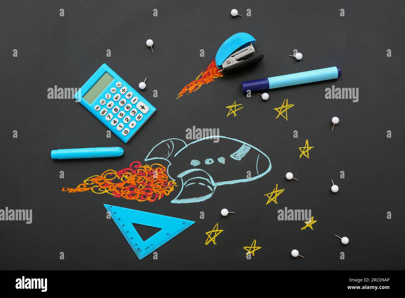 Creative composition with drawn rocket and different stationery on black chalkboard Stock Photo