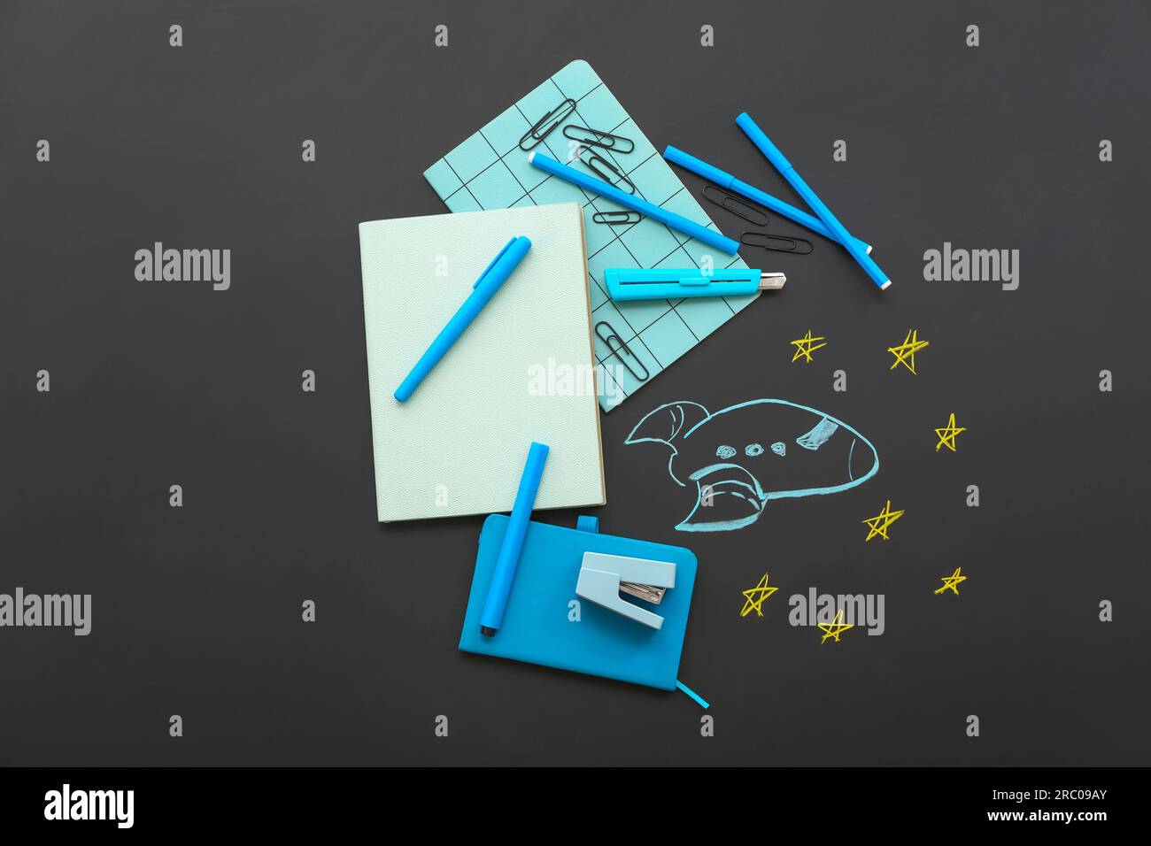 Creative composition with drawn rocket and different stationery on black chalkboard Stock Photo
