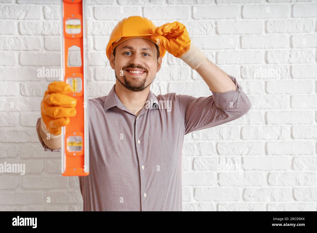 Builder Using Level Male builder with level near white brick wall Stock Photo - Alamy