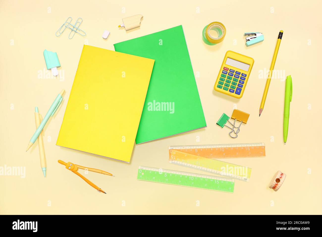 Notebooks with different stationery on pale yellow background Stock Photo
