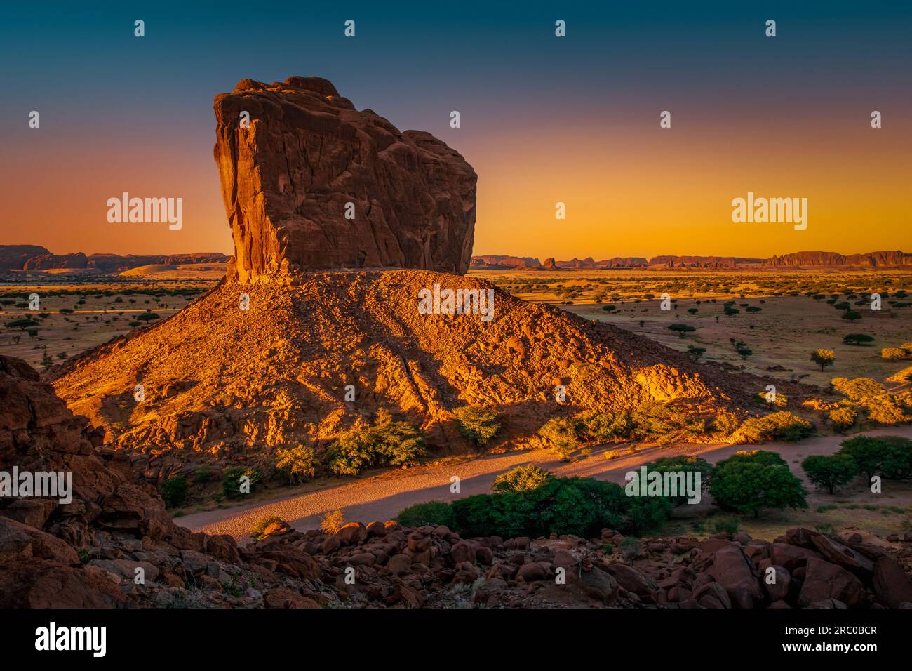 Breathtaking sunrise casting golden hues over the stoic butte, captured from the vantage point of Djoula Arch, Ennedi, Chad Stock Photo