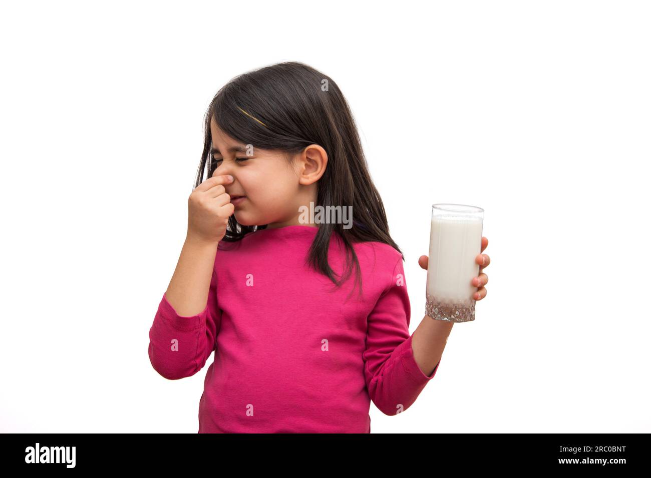 Little girl who doesn't want to drink milk on a white background Stock