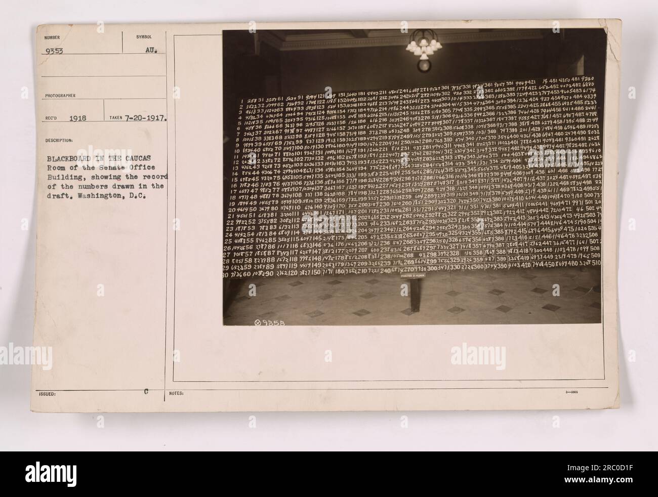 Draft numbers being drawn on a blackboard in the Caucus Room of the Senate Office Building in Washington, D.C. during World War One. The blackboard shows a record of the numbers drawn during the draft. This photo was taken on July 20, 1917. Stock Photo