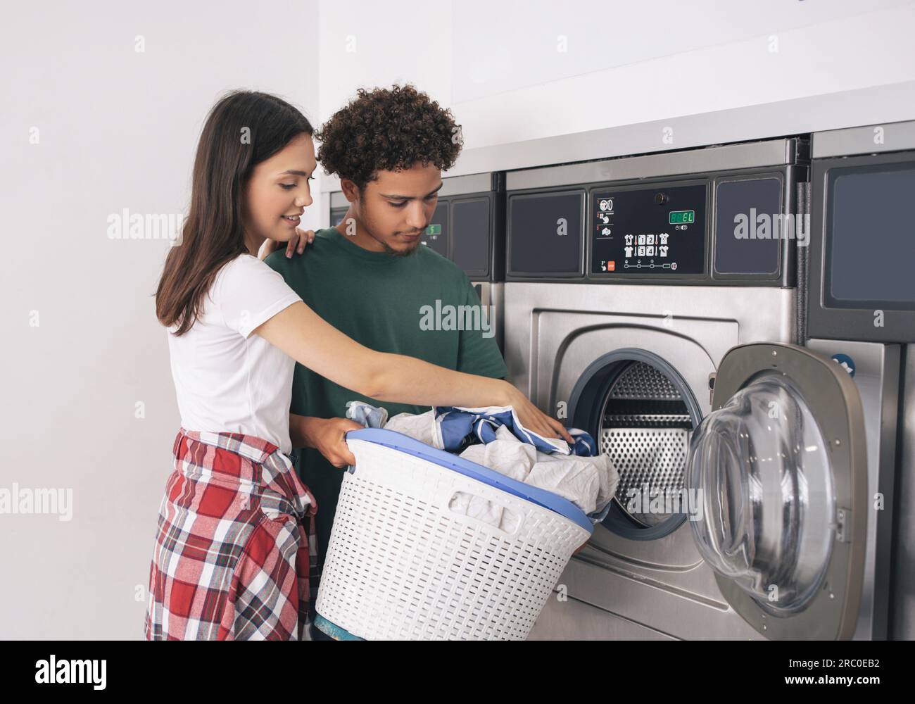 Young Man And Woman Folding Laundry Doing Chores At Laundrette Stock Photo