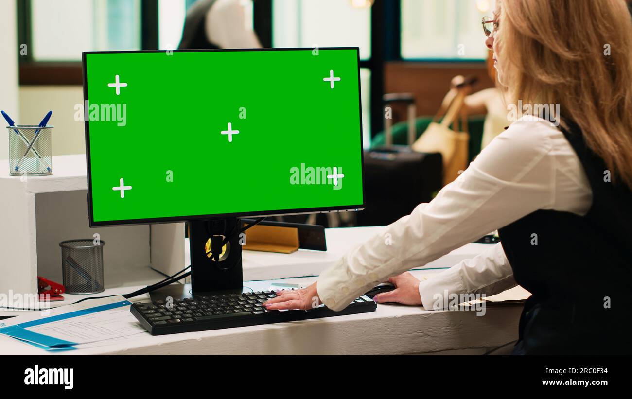 Front desk staff using greenscreen on pc in resort lobby, checking