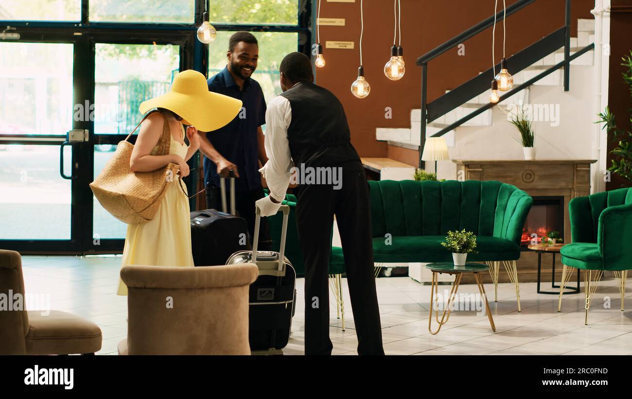Hotel bellhop providing luxury service to guests entering reception