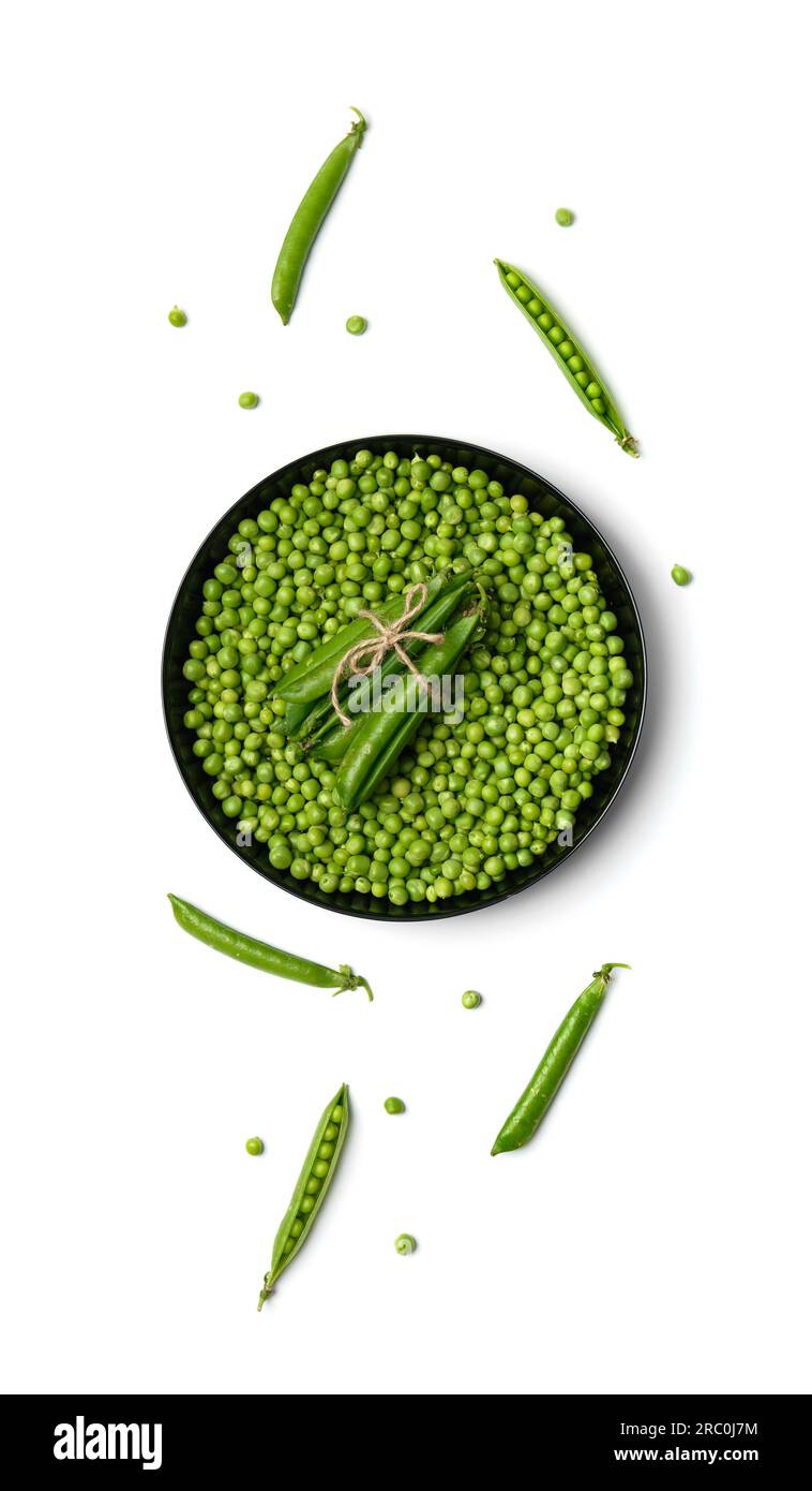 Peeled grains of fresh green peas in a round black plate and green pea pods on a white background, top view. Vegetable protein, healthy products. Stock Photo