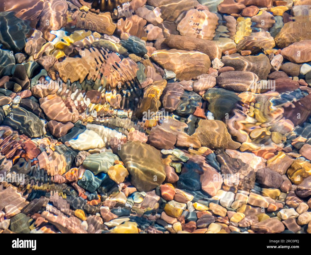 Colorful small rocks under clear water at the edge of Lake Superior in ...