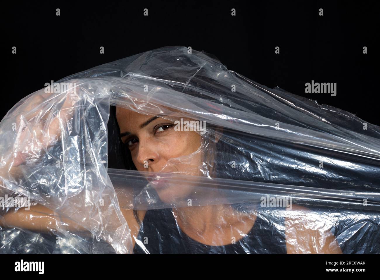 A woman with a plastic bag over her head looking through a hole