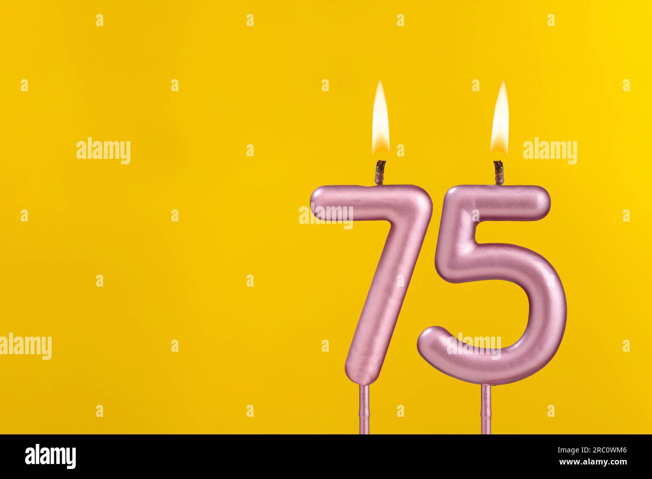 Birthday candle number 75 - Birthday celebration on yellow background Stock Photo