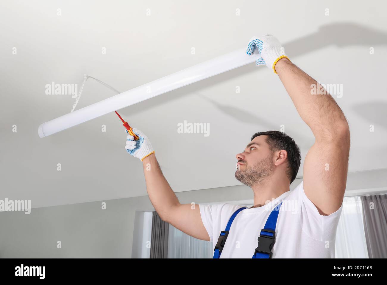 Electrician installing led linear lamp indoors. Ceiling light Stock ...