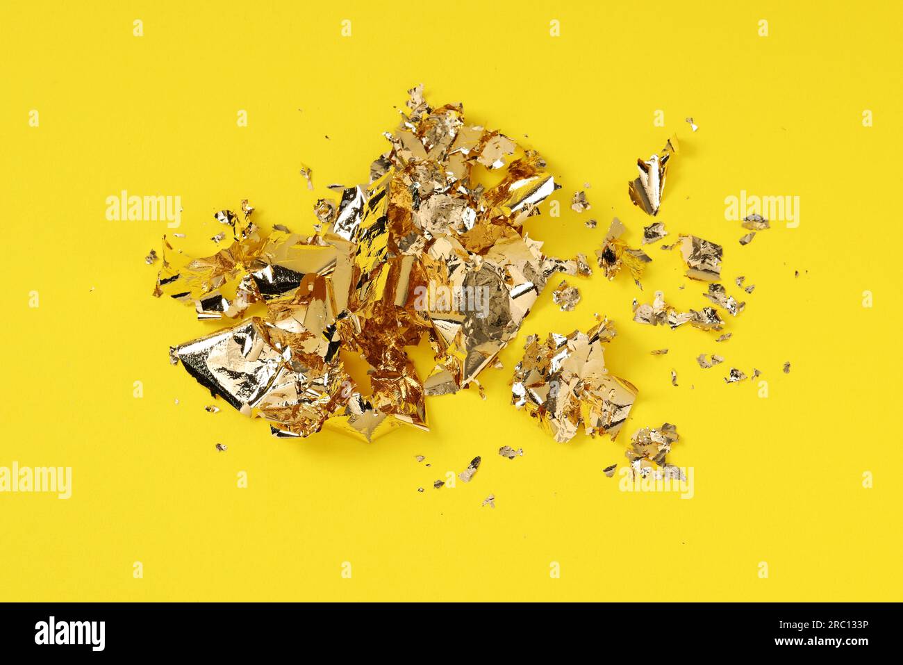 Many pieces of edible gold leaf on yellow background, above view Stock