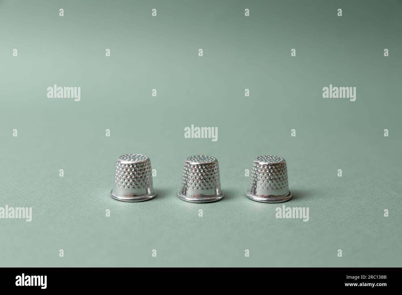 Three thimbles on pale olive background. Thimblerig game Stock Photo ...