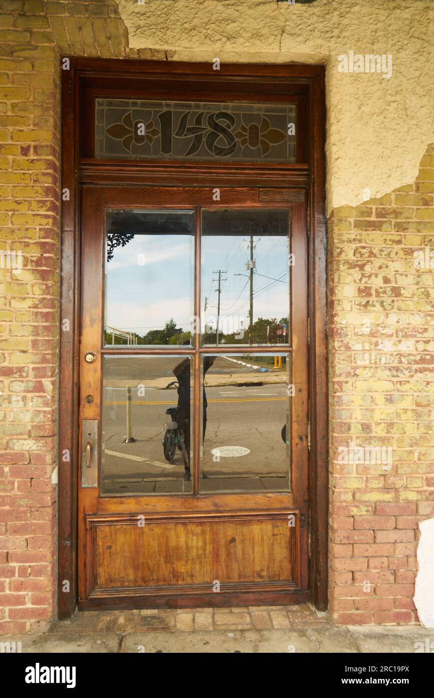 photo of a wooden door with a glass window on a brick wall in Pensacola