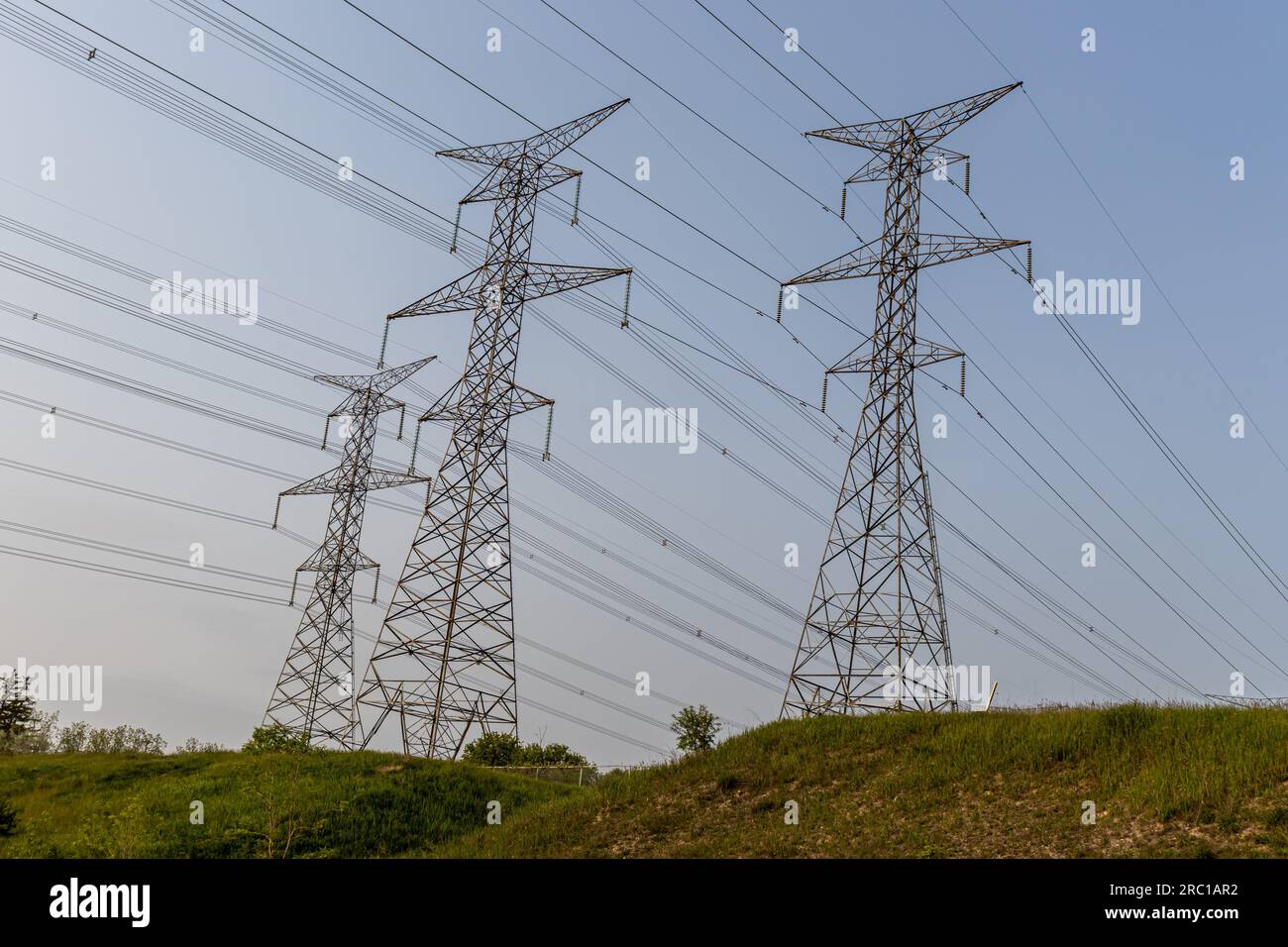 High voltage power lines - metal power grid - grass hill background. Taken in Toronto, Canada. Stock Photo