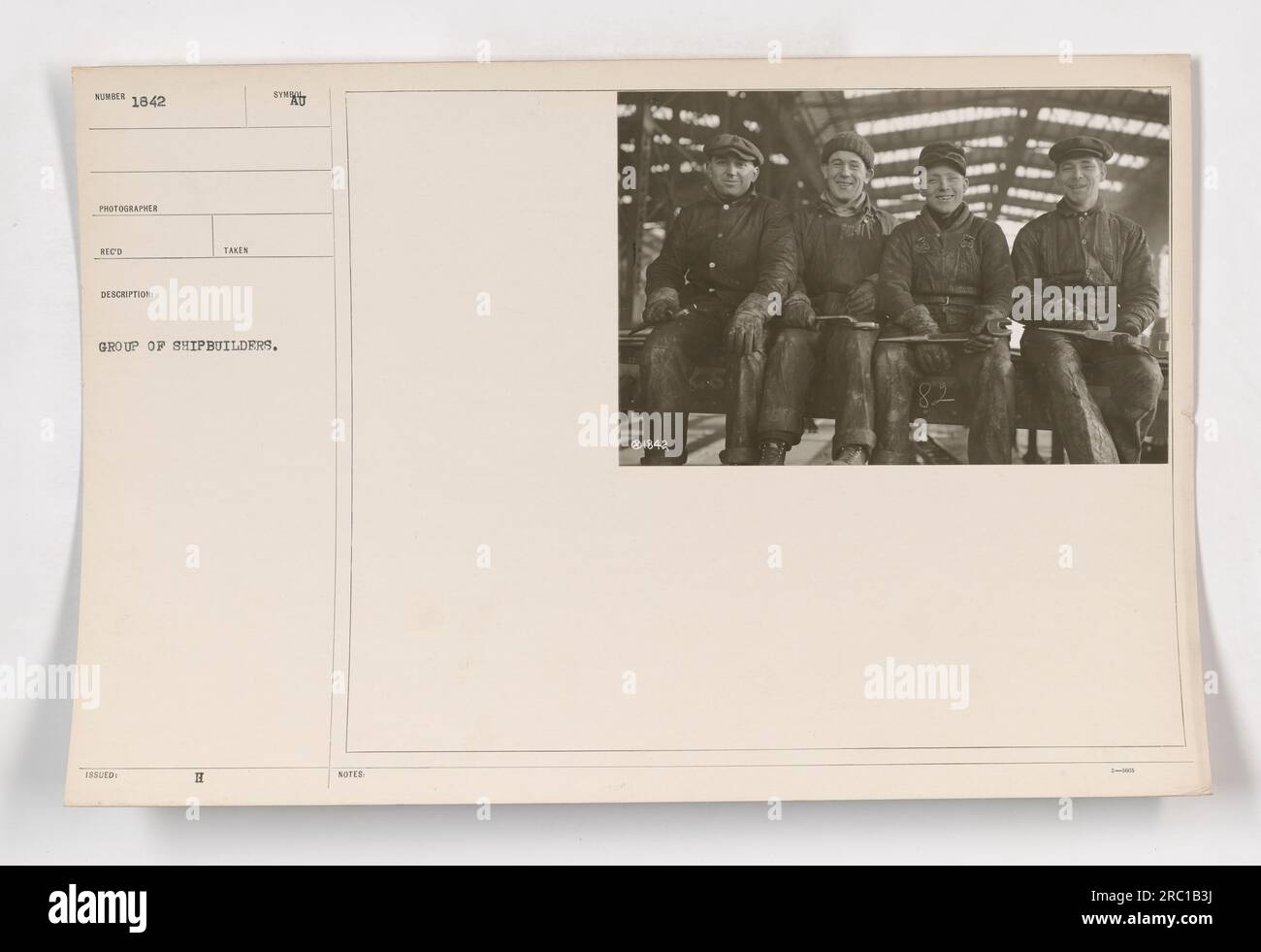 Group of shipbuilders standing in front of a ship under construction