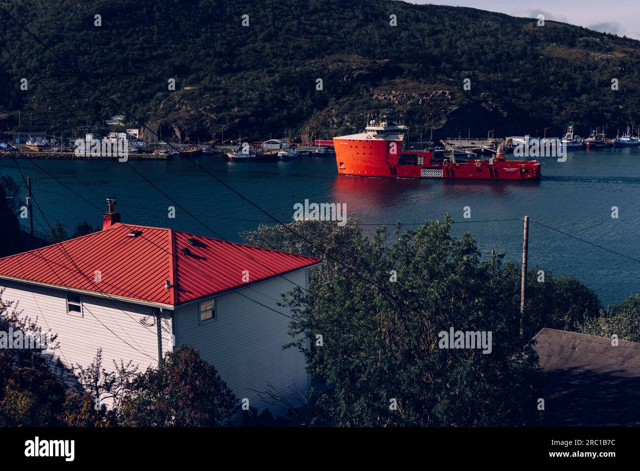 A ship sails out from the port of St. John's in an early summer morning. Stock Photo