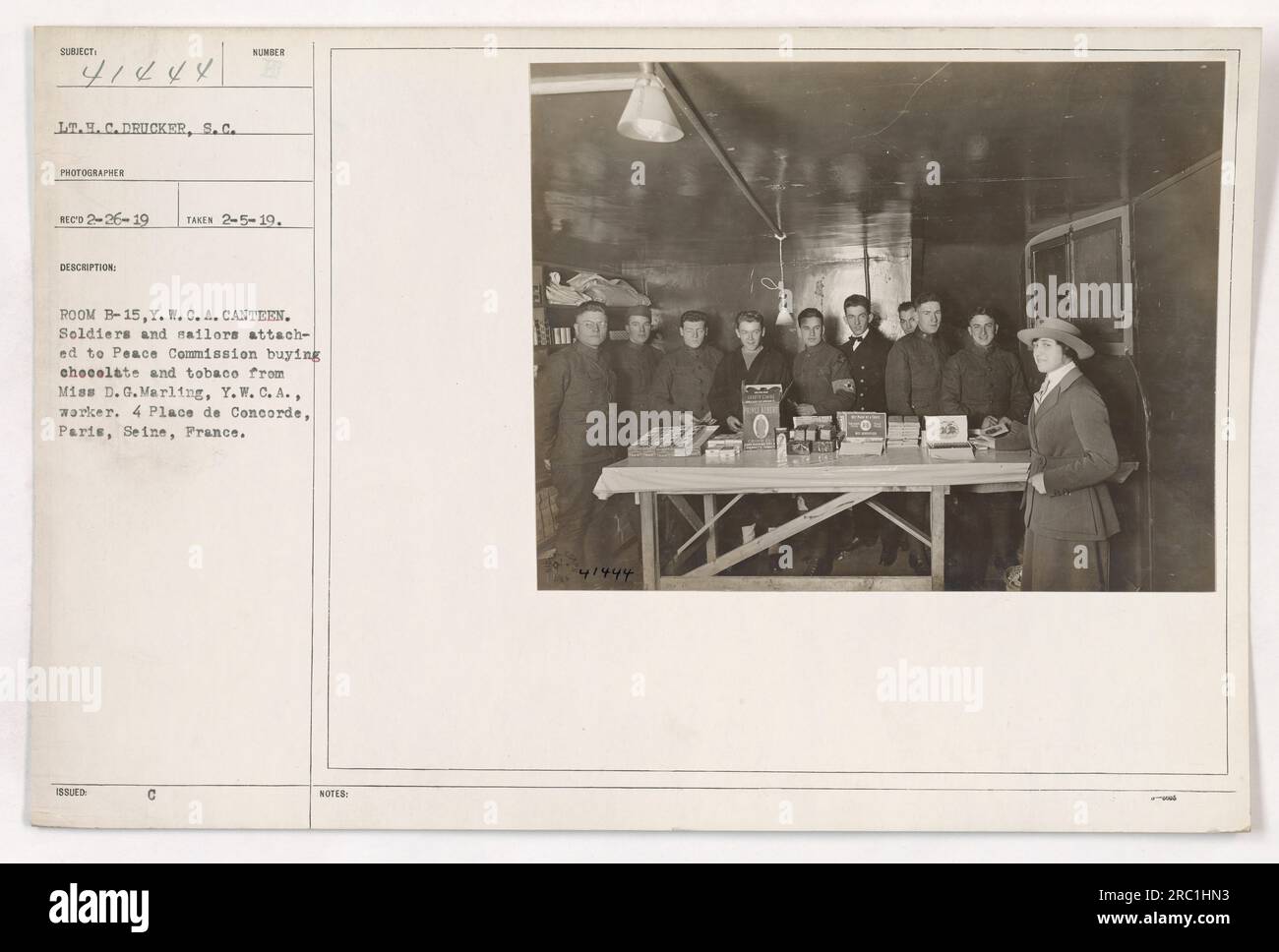 American soldiers and sailors who are part of the Peace Commission purchasing chocolate and tobacco from Miss D. G. Marling, a Y.W.C.A. worker, at the Y.W.C.A. Canteen located at 4 Place de Concorde, Paris, France. This photograph was taken on February 5, 1919, by photographer Lt. H.C. Drucker, S.C. It is cataloged with the number 111-SC-41444 and is a part of the collection from the Photographs of American Military Activities during World War One. Stock Photo