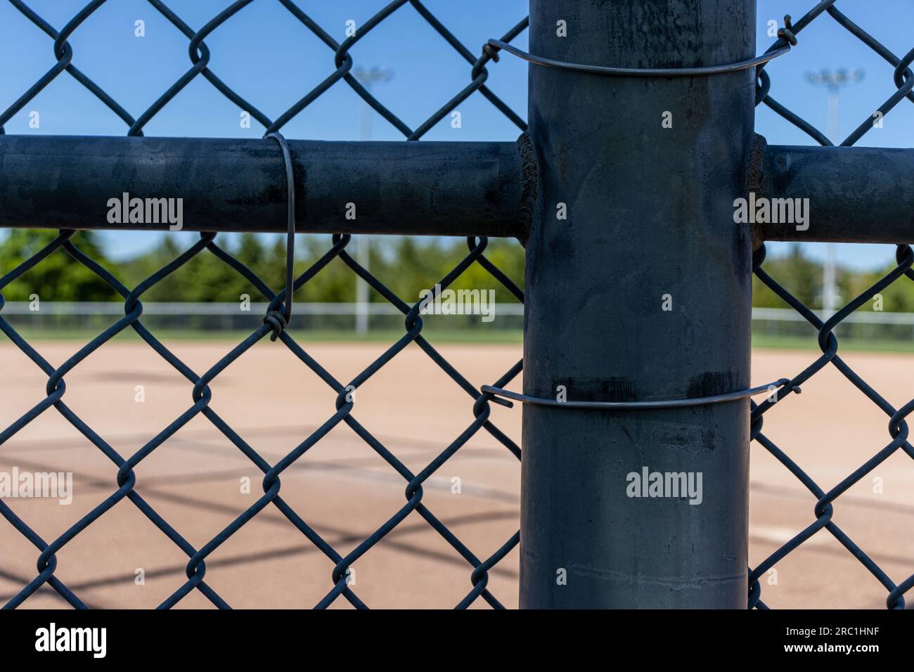 Wire metal fence cross with baseball field diamond in background. Taken