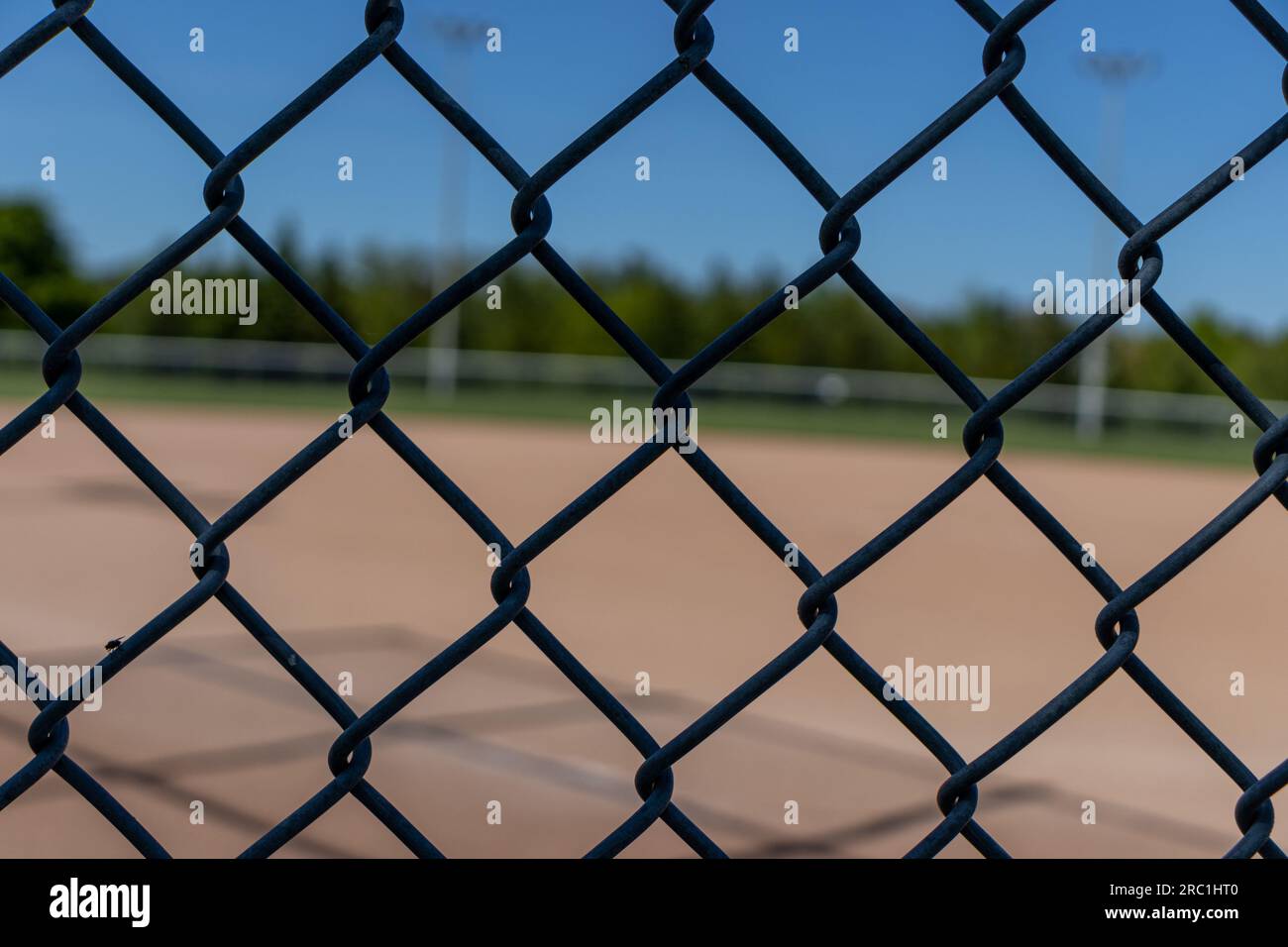 Wire metal fence with baseball field diamond in background. Taken in