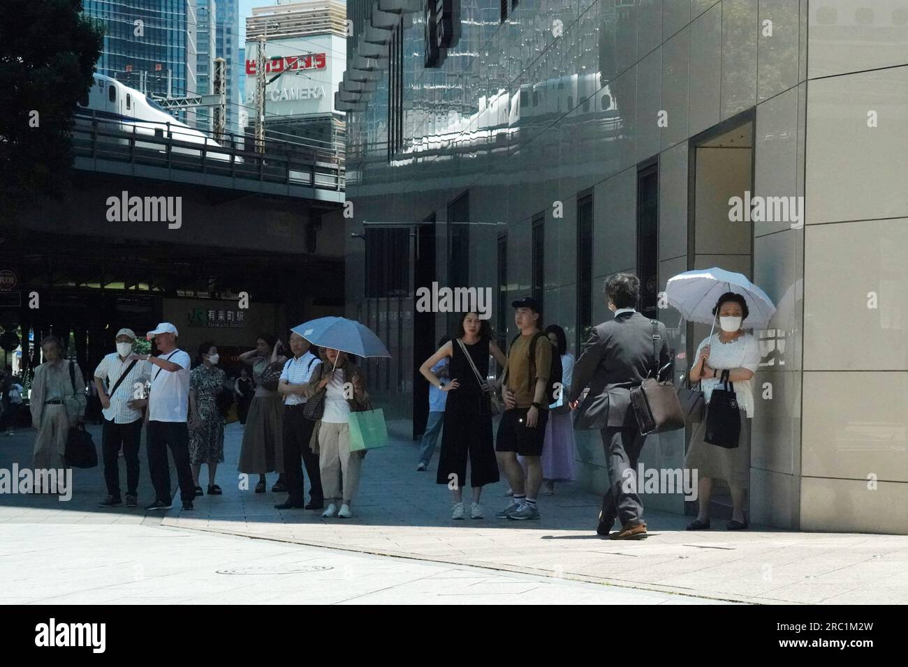 People rest in shade to wait for traffic signal Wednesday, July 12
