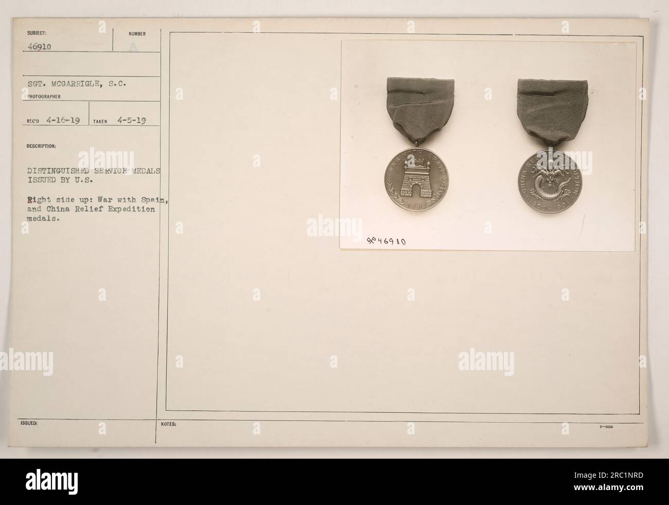 The photograph shows a close-up of two distinguished service medals issued by the U.S. military. The first medal is for the War with Spain and the second medal is for the China Relief Expedition. The medals are numbered, with the notation '946910' indicating their identification. The photograph was taken on April 5, 1919, by photographer S.C. McGarrigle, and it was later recorded in the photographer's records on April 16, 1919. Stock Photo